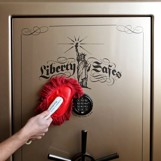 Hand using the Liberty Safe Mini Duster to remove dust from a Liberty gun safe without scratching the finish